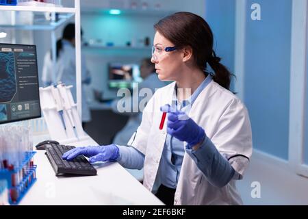Medico scienziato professionista che prende un campione per l'esperimento medico. Ricercatore chimico che lavora in laboratorio con provetta di sangue per scoprire il vaccino contro il coronavirus Foto Stock