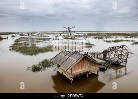 Cottage del pescatore nella palude e nella trappola quadrata del pesce di tuffo con la luce bassa nuvolosa di pioggia. Foto Stock