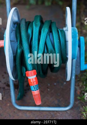 Tubo flessibile da giardino arrotolato sul supporto Foto Stock