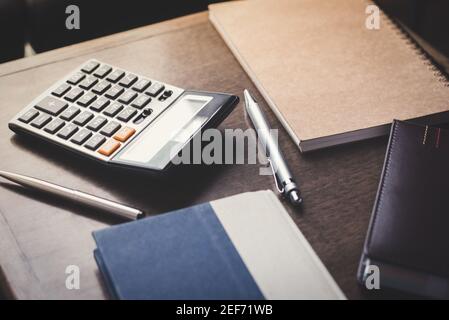 Notebook, penne e calcolatrice su tavolo in legno Foto Stock