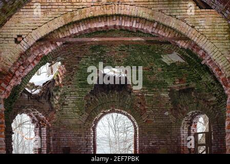 Vecchie finestre in pietra in vecchio stile russo. Mura d'epoca di una chiesa con mattoni da peeling in Russia. Bar su un'antica finestra. Foto Stock