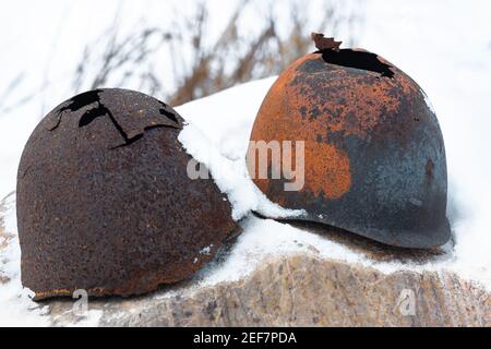 Vecchi caschi rotti la guerra mondiale sovietica sulla pietra di neve è rimasta In Federazione Russa Foto Stock