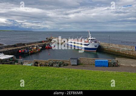 Il piccolo molo e il porto di John OÕGroats con il traghetto passeggeri Pentland Venture collegato con le barche da pesca locali. Foto Stock