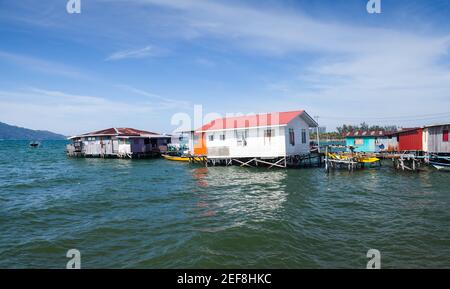 Case in legno di rickety e passerelle su palafitte. Vista costiera del quartiere povero vivente di Kota Kinabalu, Malesia Foto Stock