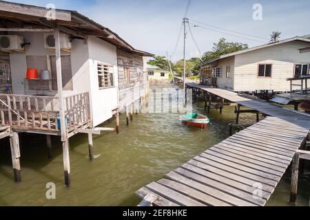 Vista sulla strada del quartiere povero di Kota Kinabalu, Sabah, Malesia. Vecchie case di legno e passerelle su palafitte Foto Stock