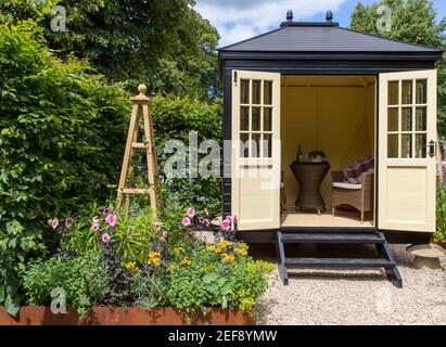 Un piccolo giardino cottage inglese con Summerhouse Shepherds Hut in ghiaia giardino - lavoro da casa ufficio - letto rialzato Flower Border - Londra UK Foto Stock