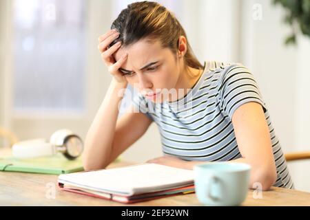 Allievo frustrato che studia le note complicate di lettura della lezione sul taccuino a. casa Foto Stock