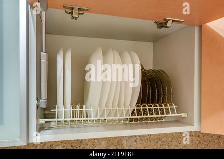 Set di piastre, tazze e bicchieri di vino sul ripiano del mobile da cucina Foto Stock