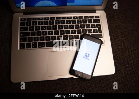 Logo Dropbox sullo schermo di uno smartphone appoggiato su un computer portatile. Dropbox è un servizio di hosting di file che offre servizi cloud e di storage Foto Stock
