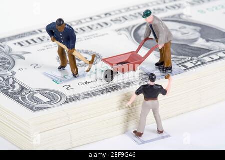 Figurine di lavoratori manuali con valuta cartacea statunitense Foto Stock