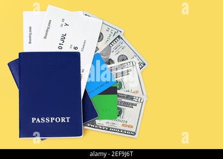 Blue Passport, carta d'imbarco, biglietto aereo, dollari usa, denaro contante USA, valuta americana, carte di credito su sfondo giallo primo piano vista dall'alto, viaggi Foto Stock