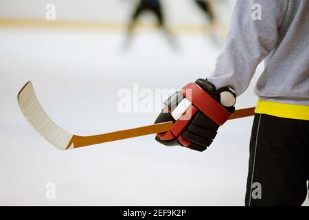 Vista in sezione intermedia di un giocatore di hockey su ghiaccio che tiene un bastone per hockey su ghiaccio Foto Stock