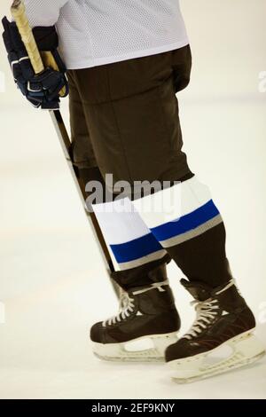 Vista in sezione bassa di un giocatore di hockey su ghiaccio che tiene un bastone per hockey su ghiaccio Foto Stock