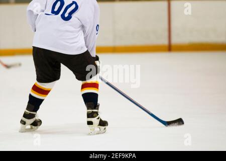 Vista posteriore di un giocatore di hockey su ghiaccio che gioca a hockey su ghiaccio Foto Stock