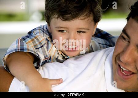 Primo piano di un ragazzo che cavalcava il piggyback sul padre Foto Stock