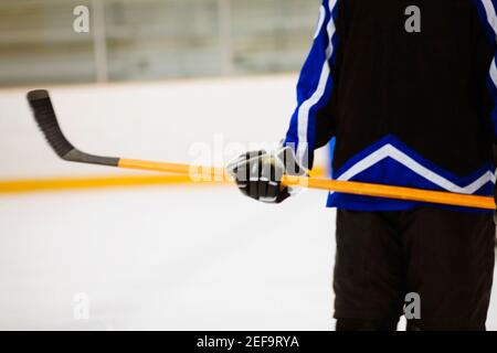 Vista in sezione intermedia di un giocatore di hockey su ghiaccio che tiene un bastone per hockey su ghiaccio Foto Stock