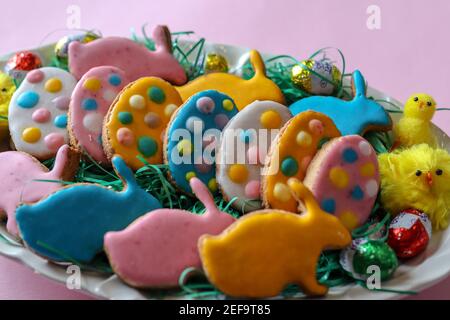 Un piatto pieno di biscotti decorati per la vacanza di Pasqua. Biscotti fatti in casa a forma di conigli e uova colorate Foto Stock