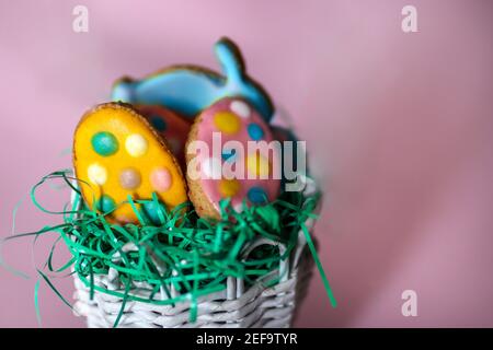 Biscotti pasquali a forma di coniglio e uova colorate isolate su sfondo rosa. Decorazione di cibo concetto di vacanza di Pasqua Foto Stock