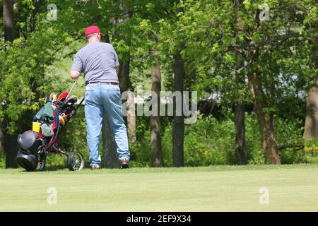 Vista posteriore di un uomo che tira una borsa da golf un carrello Foto Stock
