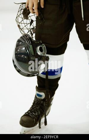 Vista in sezione bassa di un giocatore di hockey su ghiaccio che tiene un casco Foto Stock