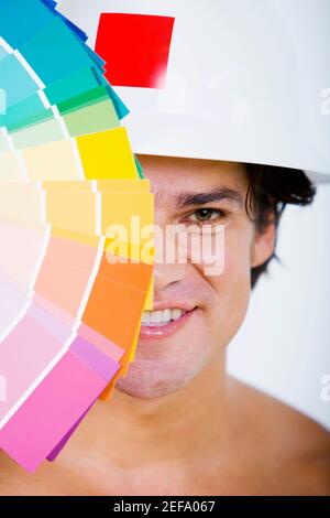 Ritratto di un uomo medio adulto che tiene campioni di colore dentro davanti al viso e sorridendo Foto Stock