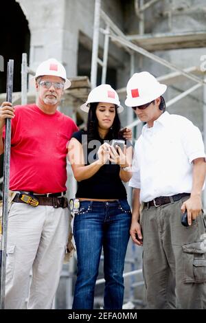 Due architetti maschi e una femmina in piedi in una costruzione sito Foto Stock