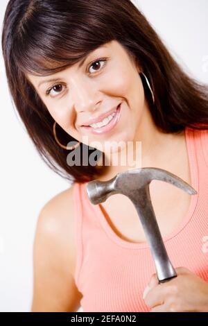 Ritratto di una giovane donna che mantiene un martello e sorridente Foto Stock