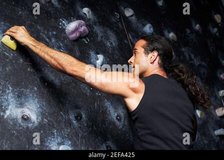 Vista posteriore di un uomo medio adulto che sale su una parete Foto Stock