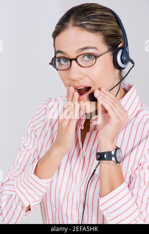 Ritratto di una donna d'affari che indossa una cuffia e che guarda sorpreso Foto Stock