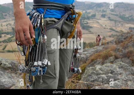 Vista in sezione intermedia di un arrampicatore maschio che trasporta la roccia attrezzature per l'arrampicata Foto Stock