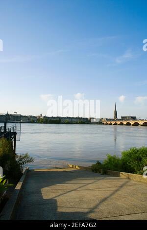 Ponte ad arco attraverso un fiume, Pont De Pierre, Basilica di San Michel, fiume Garonna, Bordeaux, Aquitaine, Francia Foto Stock