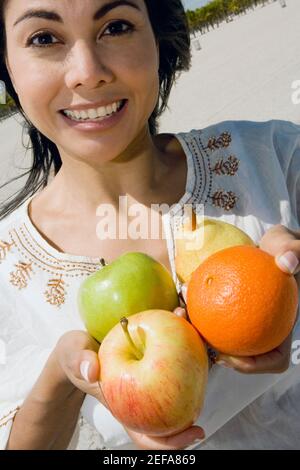 Ritratto di una donna mid adulta che tiene frutti e sorride Foto Stock