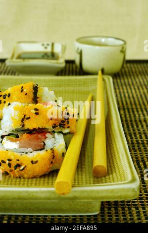 Vista ad alto angolo del sushi su un vassoio da portata con un paio di bacchette Foto Stock