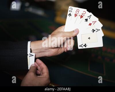 Primo piano di una mano personÅ½s che tiene le carte da gioco e si nasconde un asso nel bracciale Foto Stock