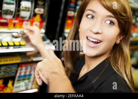 Primo piano di una giovane donna che gioca su una slot machine in un casinò Foto Stock