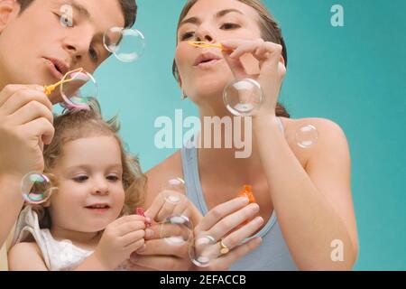 Una coppia di adulti di media età che soffia bolle con la figlia Foto Stock