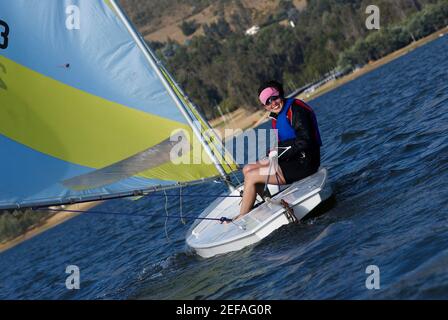 Giovane donna seduta in barca a vela e sorridente Foto Stock