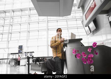 Vista ad angolo basso di un uomo medio adulto con un computer portatile in aeroporto Foto Stock