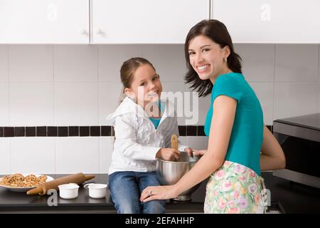 Giovane donna che fa biscotti con sua figlia in cucina Foto Stock