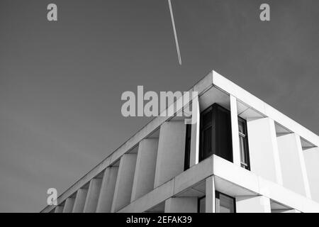 Velivolo Vapor Trail in un cielo blu chiaro sopra l'ospedale a Kortrijk, Belgio Foto Stock