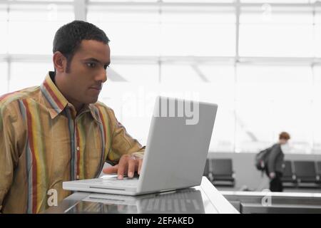 Uomo medio adulto che usa un computer portatile in un aeroporto e. un aspetto serio Foto Stock