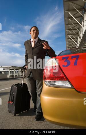 Uomo d'affari in piedi vicino ad un taxi con la presa dei suoi bagagli e. gesturing Foto Stock