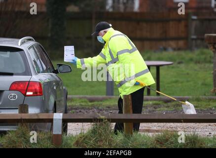 Un lavoratore di prova e di traccia nel parcheggio di Bramley Inn a Bramley, vicino Basingstoke, Hampshire mostra una scheda di registrazione di prova del coronavirus ad un driver ad un programma di test di pompaggio con residenti locali, dopo che un caso della variante sudafricana di Covid-19 è stato identificato nel villaggio. Data immagine: Mercoledì 17 febbraio 2021. Foto Stock