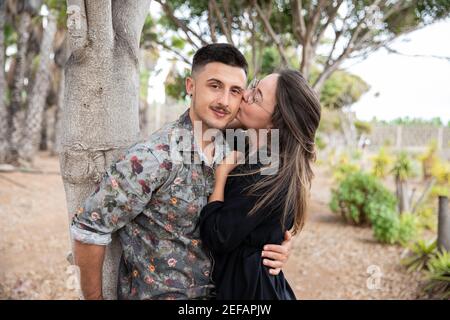 La fidanzata dà un bacio sulla guancia del suo ragazzo, una giovane coppia in amore scambio coccole. Foto Stock