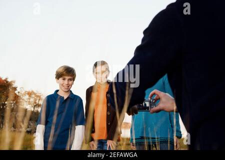 Vista posteriore di un uomo che fotografa la sua famiglia Foto Stock