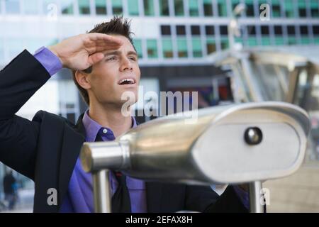 Primo piano di un uomo d'affari con binocolo gestito da Coin operated di fronte lui Foto Stock