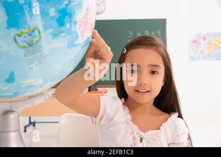 Ritratto di una studentessa che punta su un globo Foto Stock