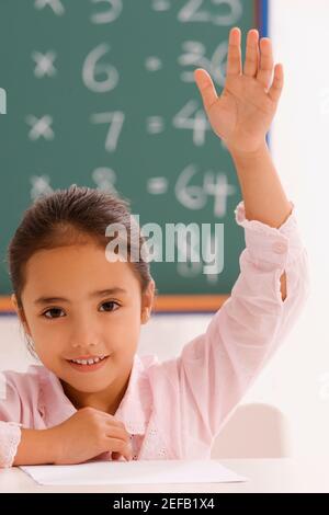 Ritratto di una studentessa con la mano sollevata in un in aula Foto Stock