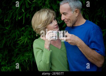 Primo piano di un uomo anziano con una donna matura che tiene tazze da tè e guardarsi l'un l'altro Foto Stock