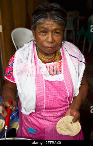 Ritratto di una donna anziana che tiene tortilla e cucina, Cuetzalan, Stato di Puebla, Messico Foto Stock